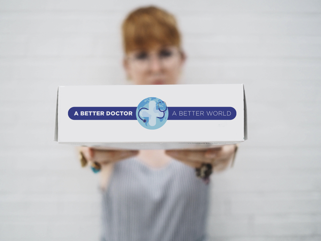 A red haired woman with glasses holding a box with a designed logo for A Better Doctor